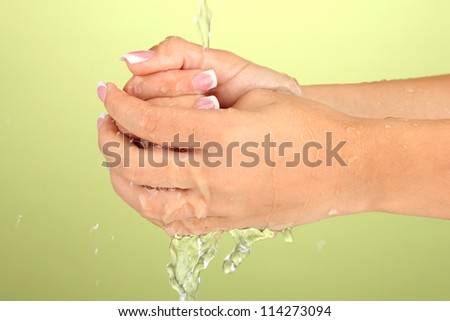 Washing woman\'s hands on green background close-up