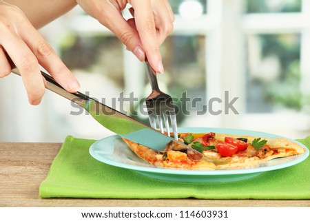 woman\'s hands cut a slice of pizza close-up
