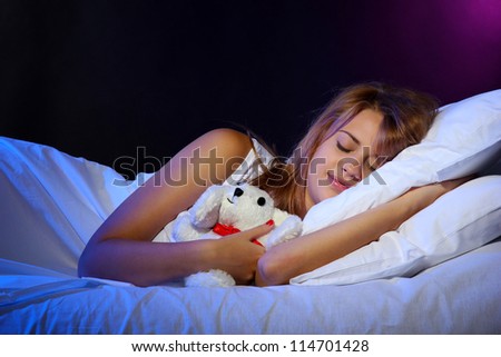 young beautiful woman with toy rabbit sleeping on bed in bedroom
