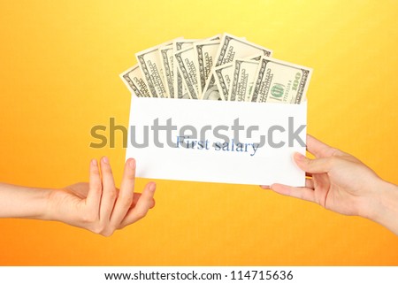 Woman\'s hand passes the envelope with the salary on yellow background