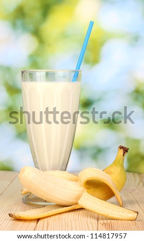 Banana milk shake on wooden table on bright background