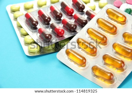 Capsules and pills packed in blisters, on blue background