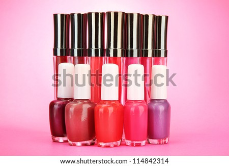 beautiful lip glosses and nail polish bottles, on pink background