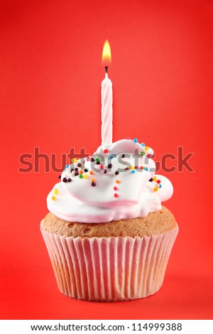 tasty birthday cupcake with candle, on red background