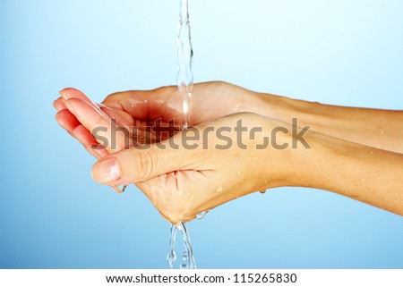 Washing hands on blue background close-up