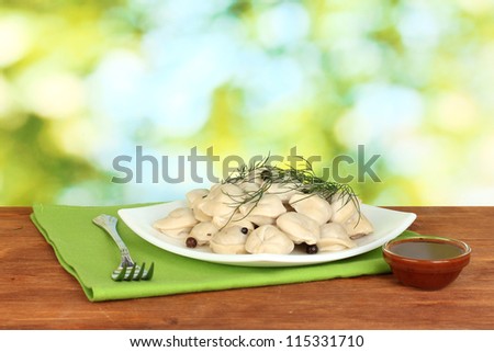Delicious cooked dumplings in the dish on bright green background