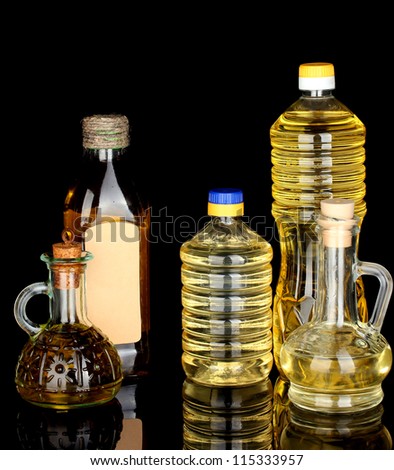 Olive and sunflower oil in the bottles and small decanters isolated on black background close-up