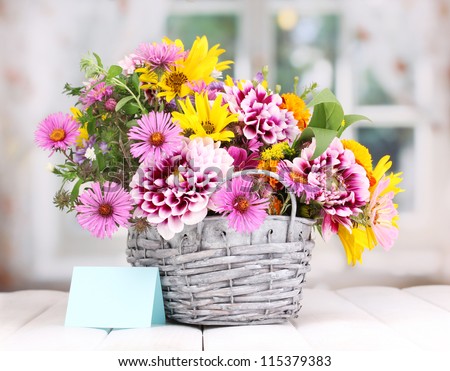 beautiful bouquet of bright flowers in basket on wooden table