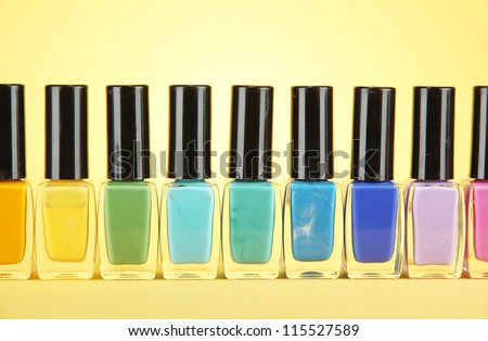 Group of bright nail polishes, on yellow background