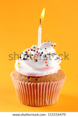 tasty birthday cupcake with candle, on orange background