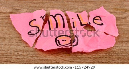 Torn paper with words Smile close-up on wooden table
