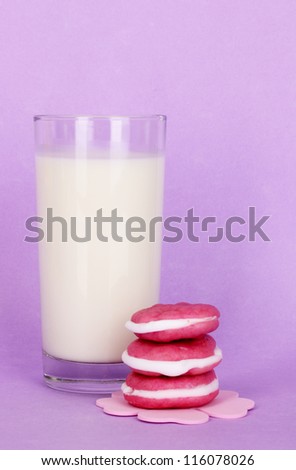 Glass of fresh new milk with cakes on purple background