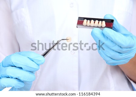 Dental tweezers and denture in dentists hands