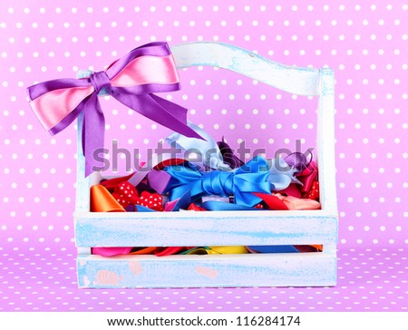 bows in wooden box on color background