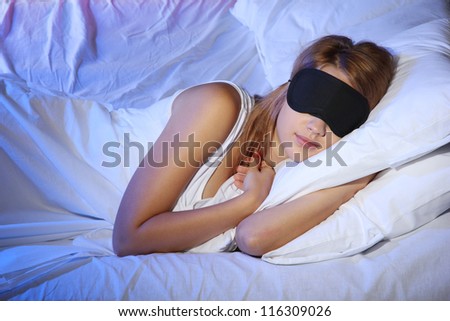 young beautiful woman with eye mask sleeping on bed in bedroom