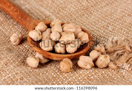 White chickpeas over wooden spoon on sackcloth background