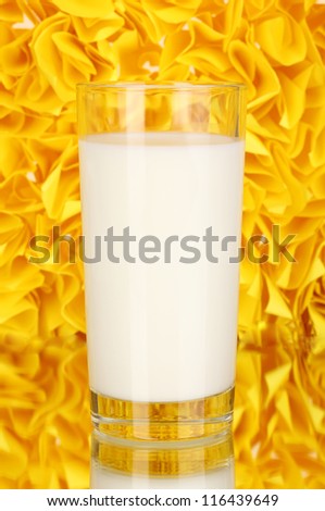 Glass of fresh new milk on decorative yellow background with reflection