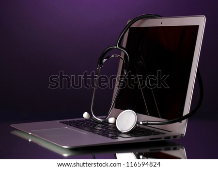 Silver notebook with a stethoscope on purple background with reflection