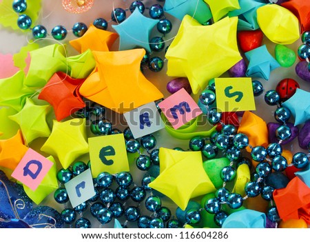 The word Dreams on colorful paper stars with dreams, beads, colorful pebbles close-up