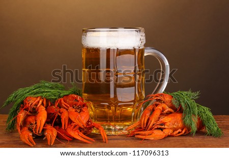 Tasty boiled crayfishes and beer on table on brown background