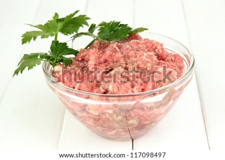 Bowl of raw ground meat on wooden table