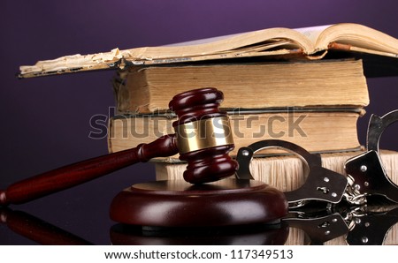 Gavel, handcuffs and books on law on purple background