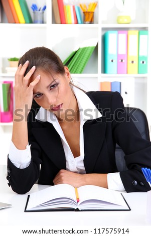 Tired business woman with documents in her workplace