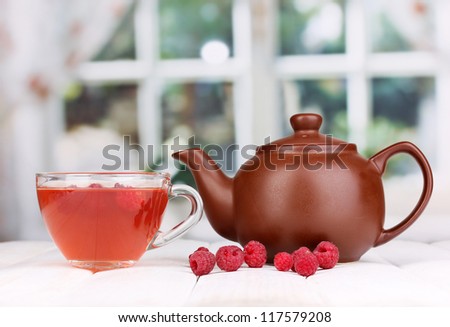 tea with raspberries on table on bright background