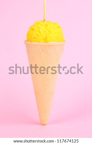 Scoop of the lemon ice cream in the waffle cone on pink background