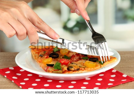 woman\'s hands cut a slice of pizza close-up