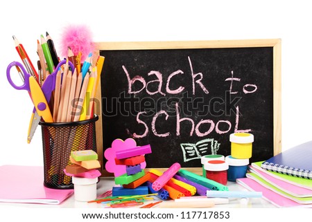 The words \'Back to School\' written in chalk on the small school desk with various school supplies close-up isolated on white