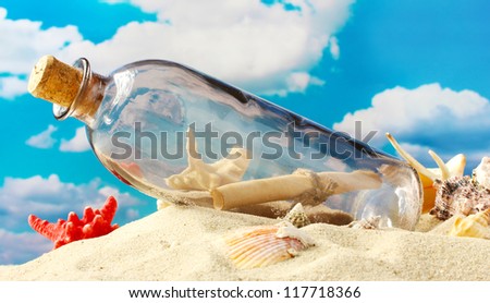 Glass bottle with note inside on sand, on blue sky background