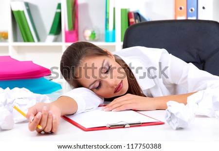 Tired business woman with documents sitting at the table and sleeps