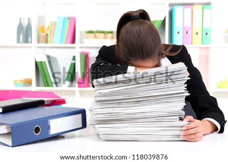 Tired business woman with documents in her workplace