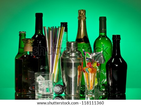 Collection of drinks, cocktail shaker and  other bartender equipment on color background