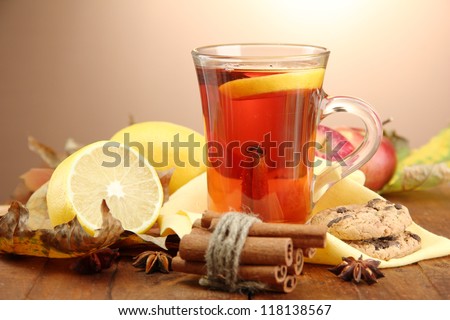 cup of hot tea and autumn leaves, on brown background