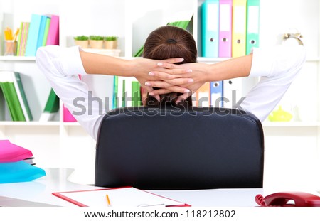 Business woman relaxing in office with hands behind head