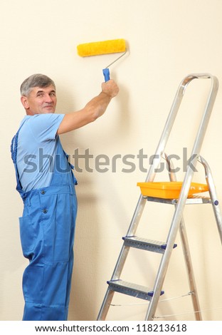 Male painter paints wall in room close-up