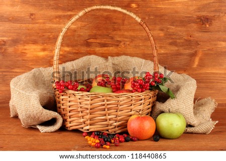 crop of berries and fruits in a basket on wooden background close-up