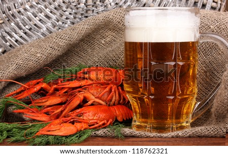 Tasty boiled crayfishes and beer on table on sackcloth background