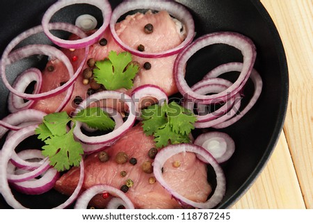 A pieces of pork with onions fried in pan close-up on wooden table