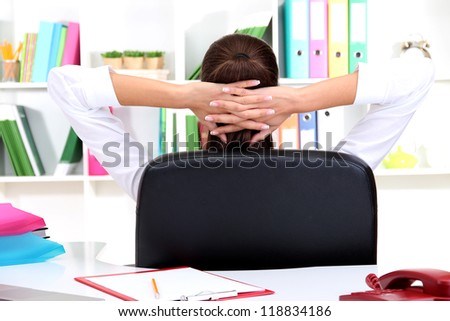 Business woman relaxing in office with hands behind head