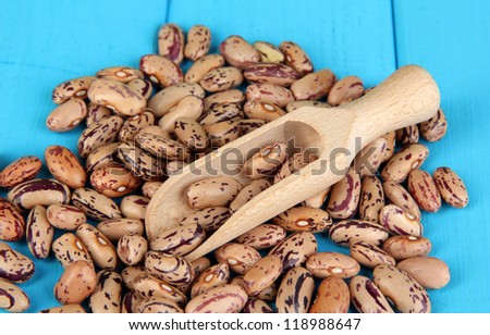 Brown beans in wooden spoon close-up on blue wooden table