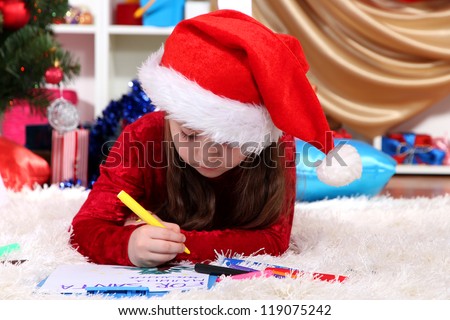 Beautiful little girl writes letter to Santa Claus in festively decorated room