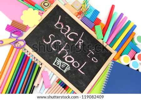The words \'Back to School\' written in chalk on the small school desk with various school supplies close-up