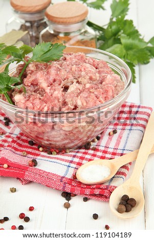 Bowl of raw ground meat with spices on wooden table