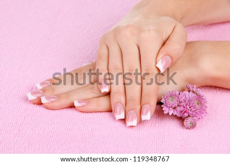 Woman hands with french manicure and flowers on pink towel