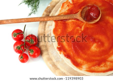 Pizza dough with tomato sauce on wooden board isolated on white