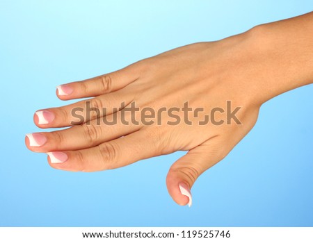 Beautiful woman\'s hand with french manicure on blue background