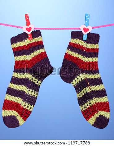 Pair of knit striped socks hanging to dry over blue background